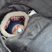 Newborn baby bundled up for winter in a baby carrier