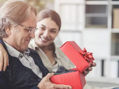 Daughter giving father a gift wrapped in a red box with a red bow