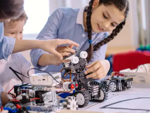 Three kids building a small robot