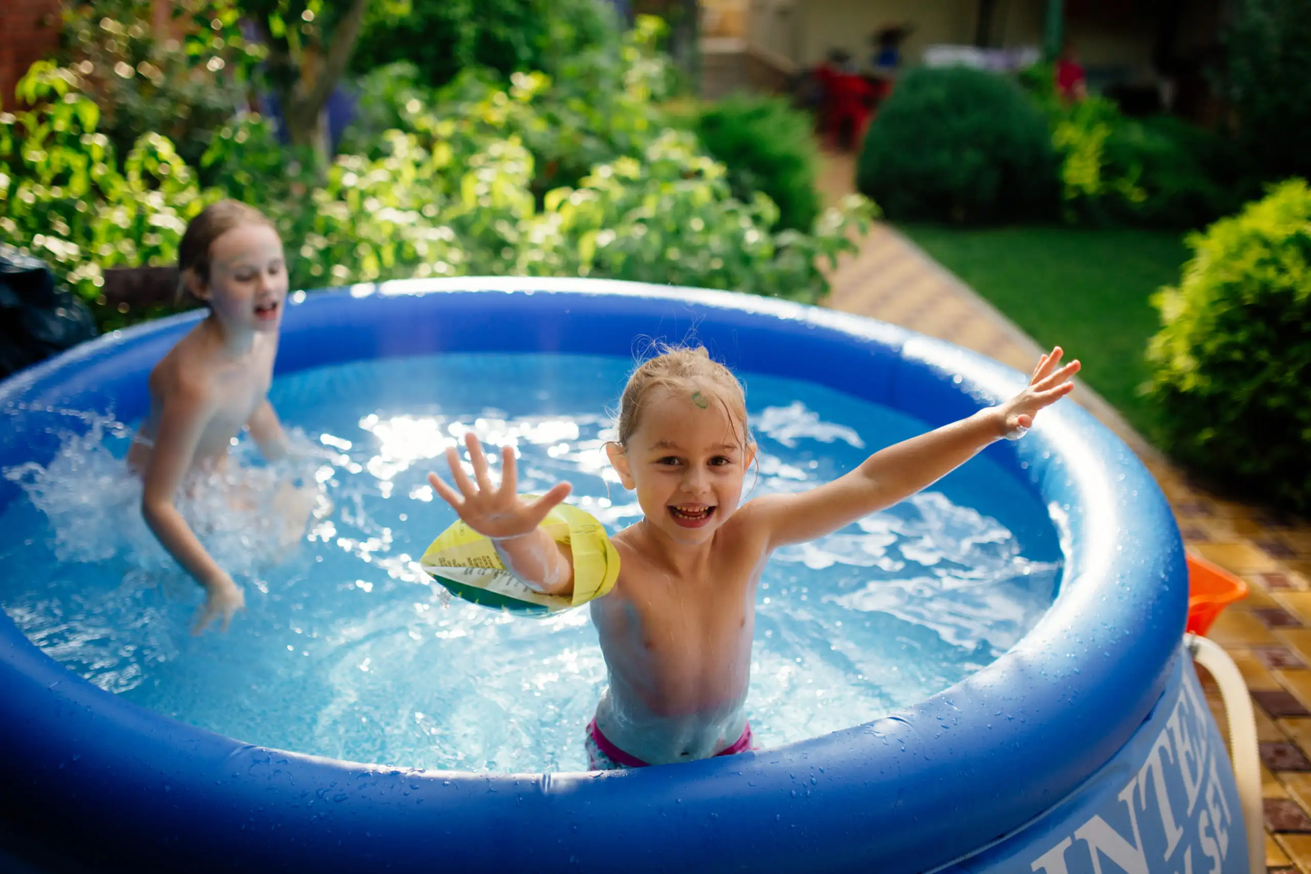 Two siblings splashing in kiddie pool