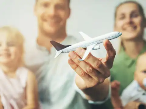 Family sitting together on couch while the father holds out a model airplane to the camera