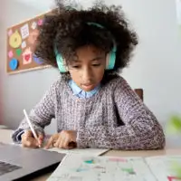 Girl wearing headphones and doing homework