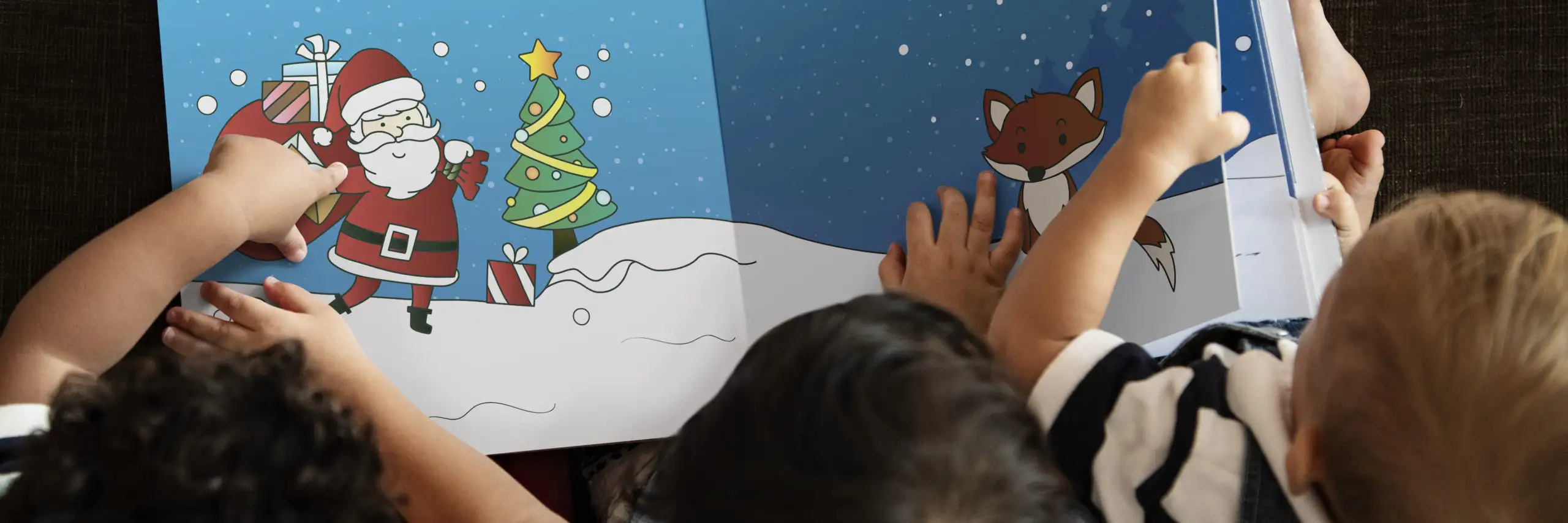 Over-the-shoulder view of three children reading a Christmas storybook