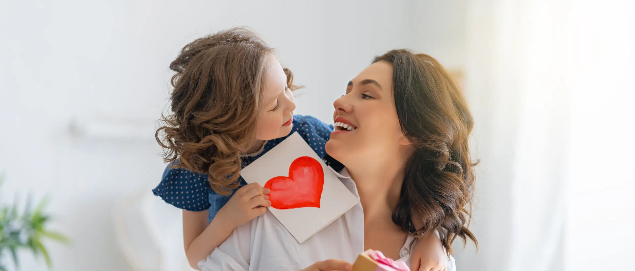 Child giving her mother a card and a gift