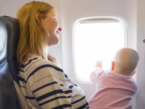 baby on moms lap in flight; Courtesy of Kaspars Grinvalds / Shutterstock