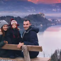 family posing for photo on lake bled in slovenia wearing weinter gear; Courtesy of Natalia Deriabina/Shutterstock