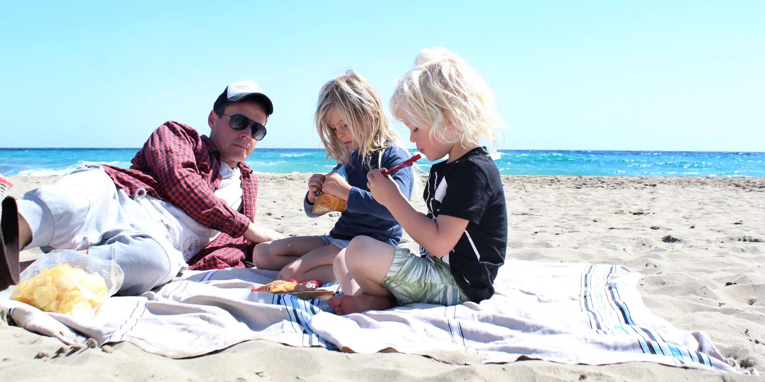 Family on a beach blanket in the sand.; Courtesy of Twenty20