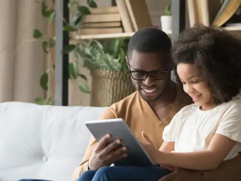 Father and Daughter Listen to Audiobook; Courtesy of fizkes/Shutterstock.com