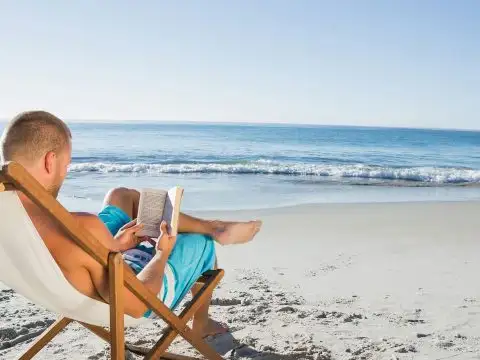 Man Reading a Book on the Beach; Courtesy of wavebreakmedia/Shutterstock.com