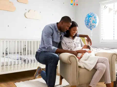 parents holding newborn in baby room; Courtesy Monkey Business Images/Shutterstock