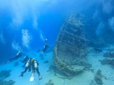 divers underwater nearing a shipwreck; Courtesy of Stas Moroz/Shutterstock