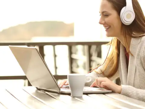 teenager using laptop and headphones on vacation; Courtesy of Antonio Guillem/Shutterstock