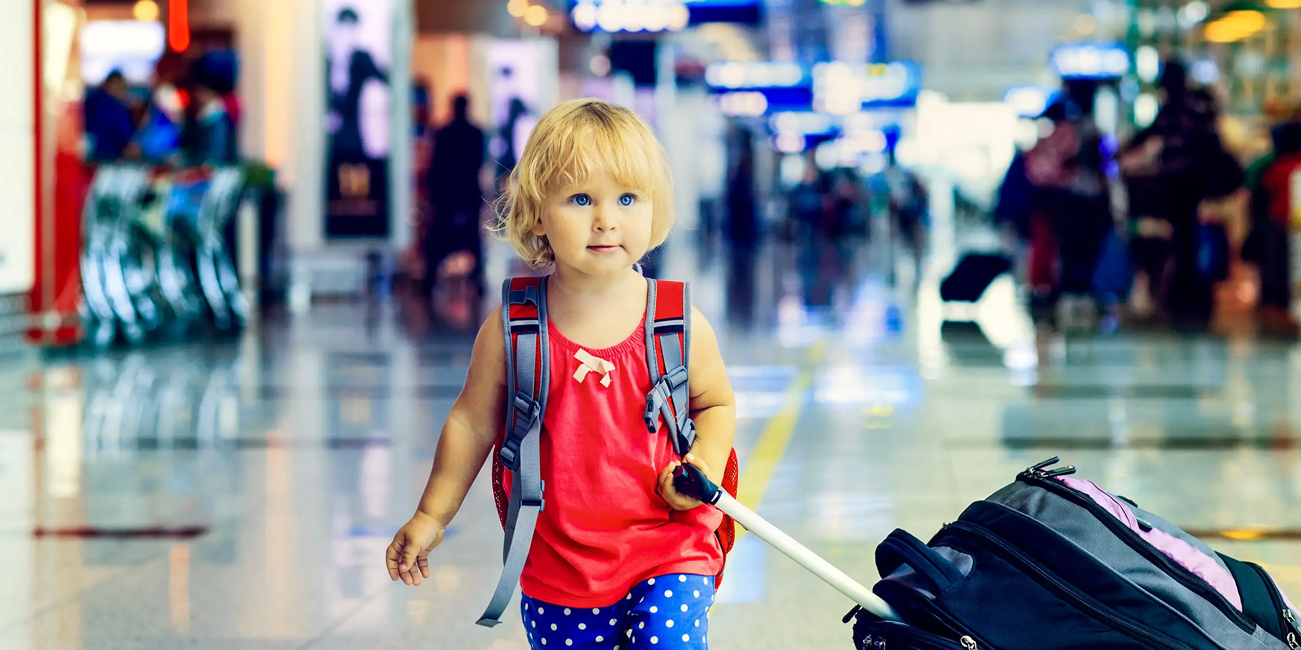 ittle girl with suitcase travel in the airport; Courtesy of NadyaEugene/Shutterstock