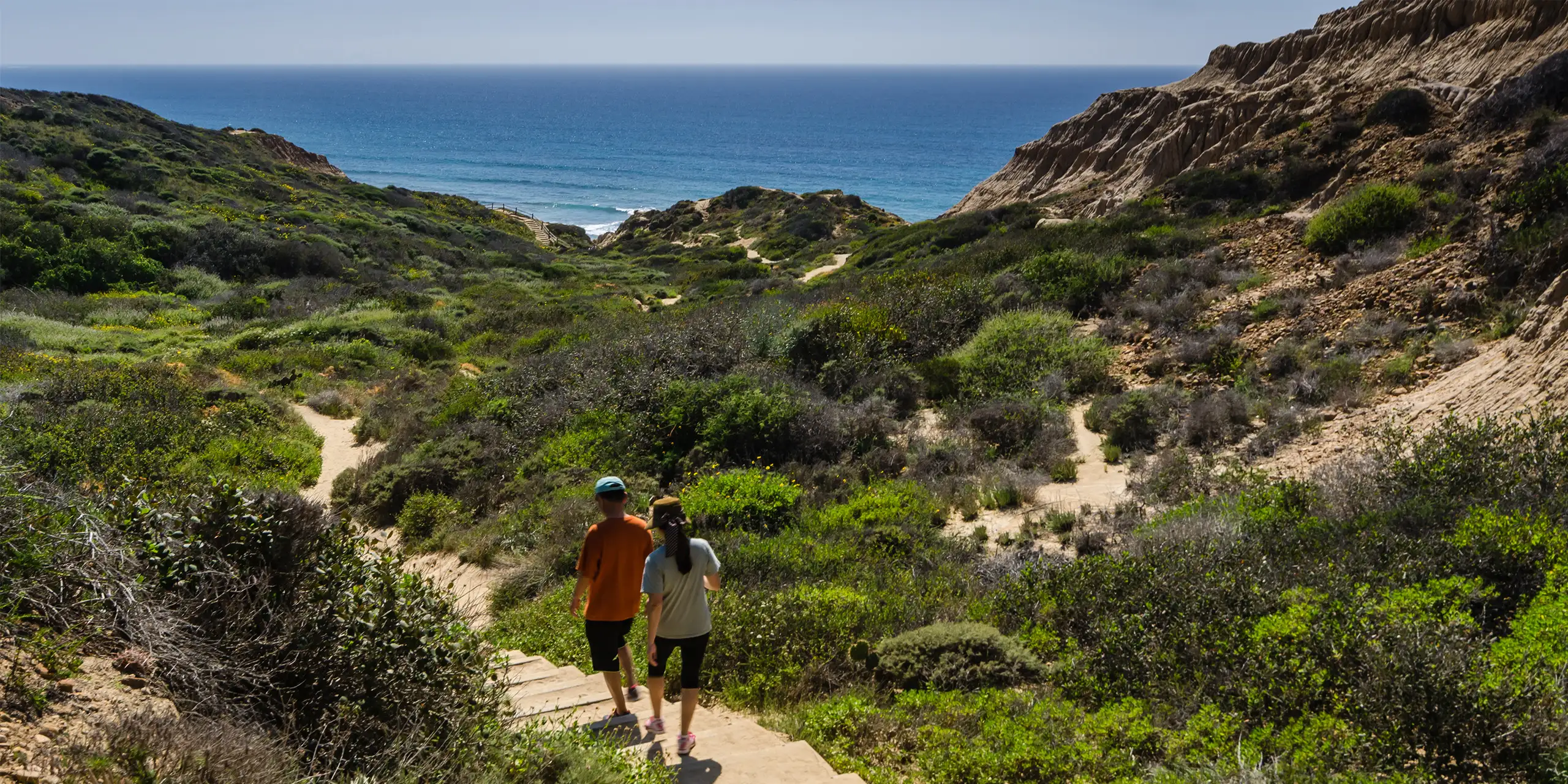 two people walking down steps to torrey pines beach in san diego